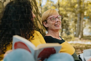 a woman reading a book next to a tree