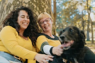 a couple of women sitting next to a dog