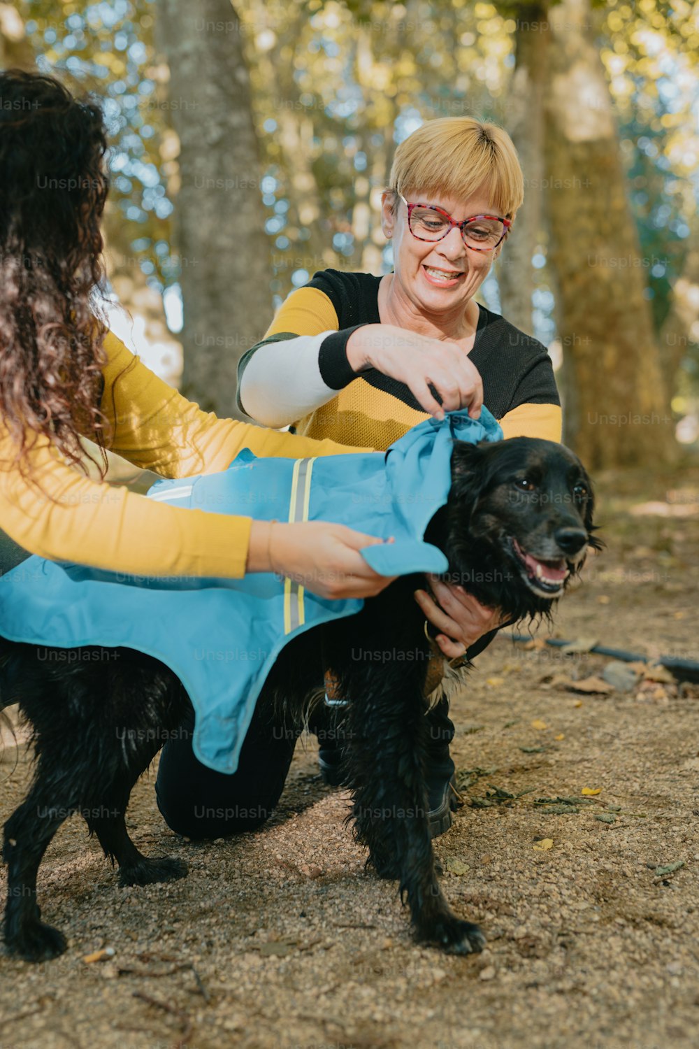 a woman holding a black dog in a park