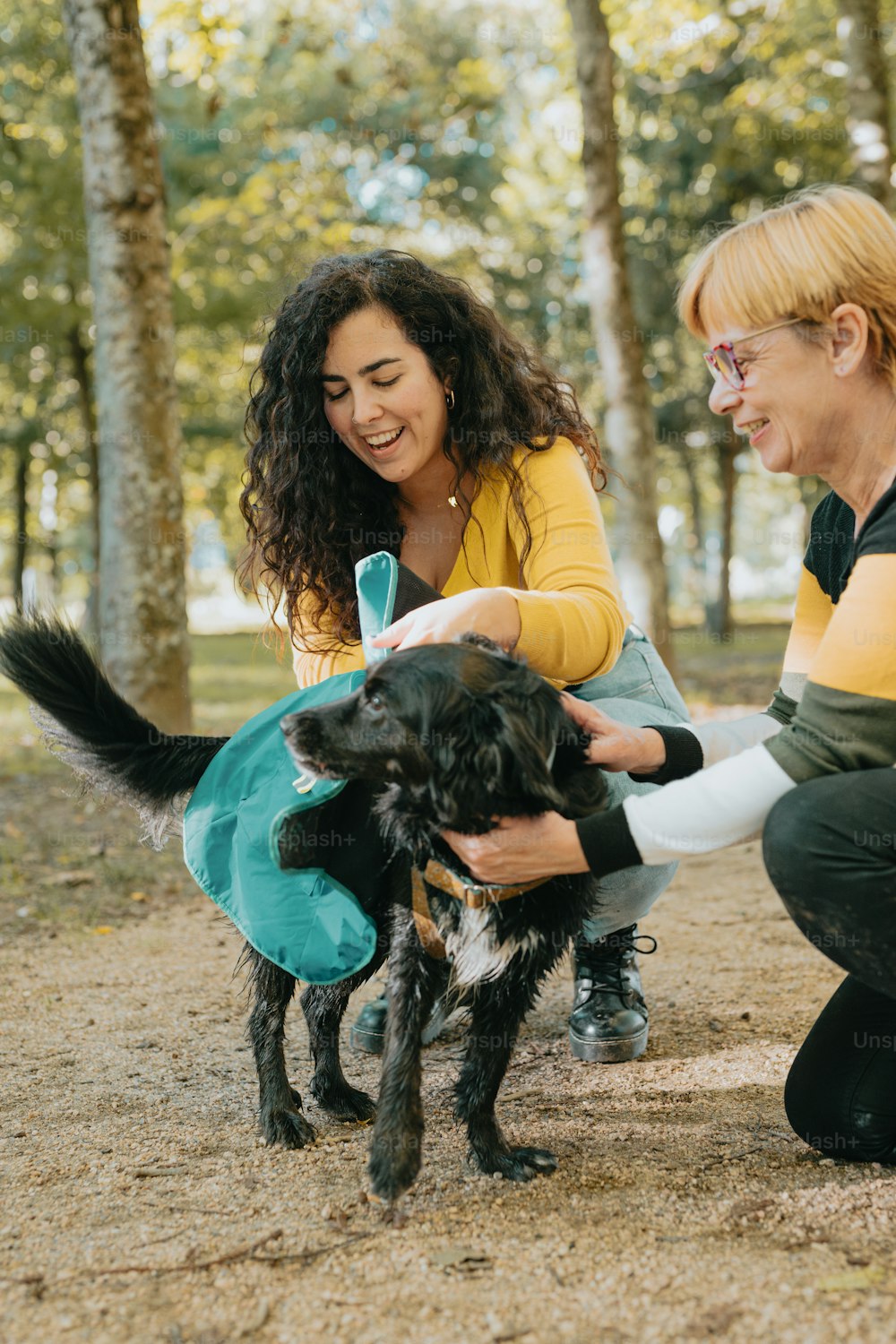 two women petting a dog in the woods