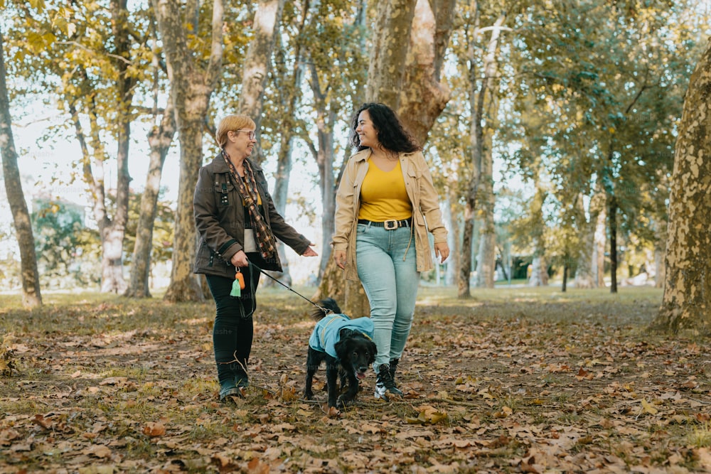 a couple of women walking a dog through a forest