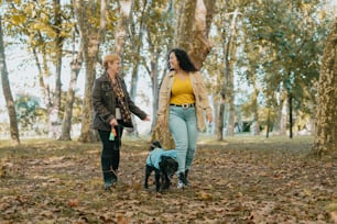 Una pareja de mujeres paseando a un perro por un bosque