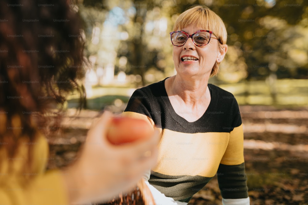 a woman holding a hot dog in a park