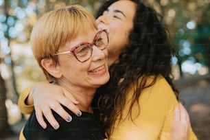 two women hugging each other in a park