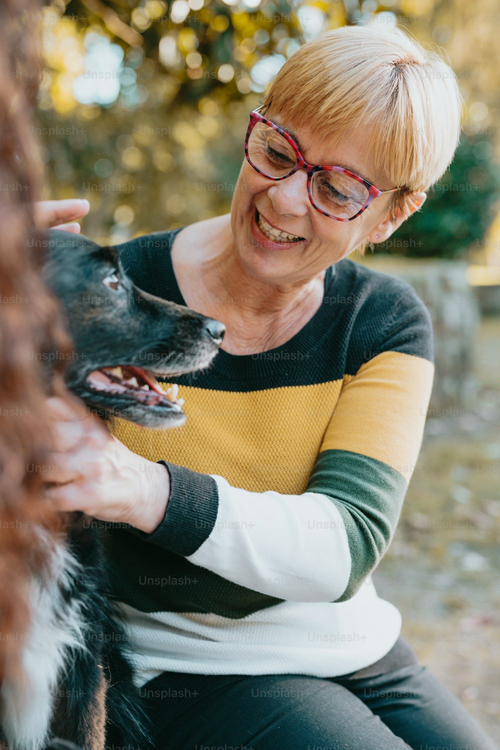 a woman in glasses petting a dog outside