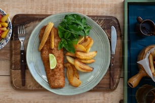 a plate of fish, fries, and fruit on a table