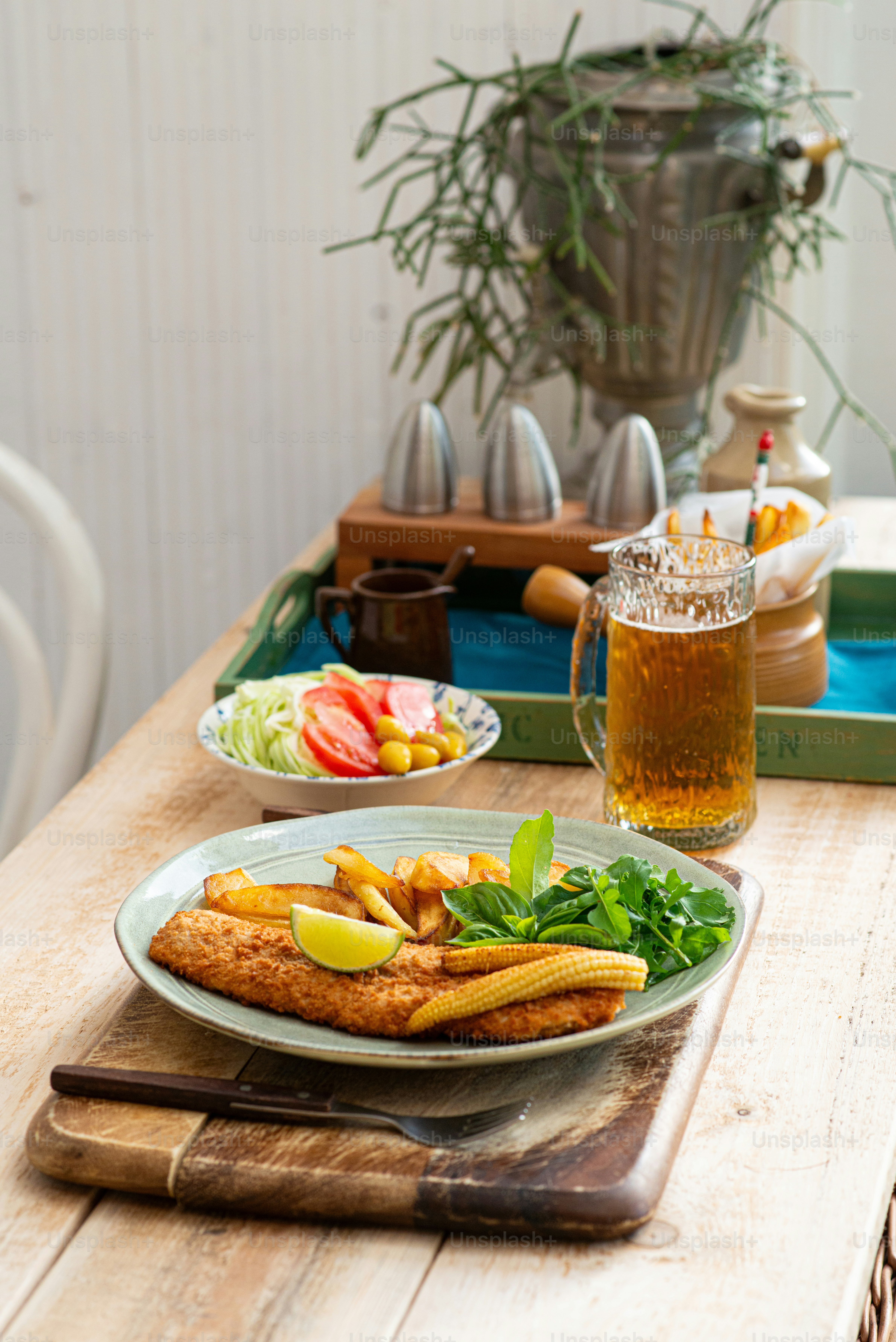 a wooden table topped with a plate of food and a glass of beer
