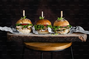 three hamburgers sitting on top of a wooden table