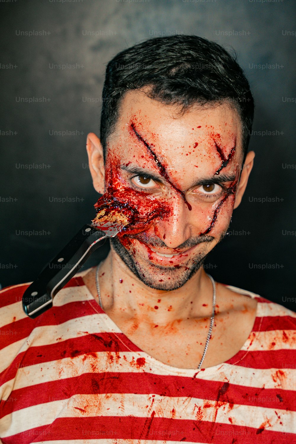 Ein Mann mit einem Messer im Mund und Blut im ganzen Gesicht