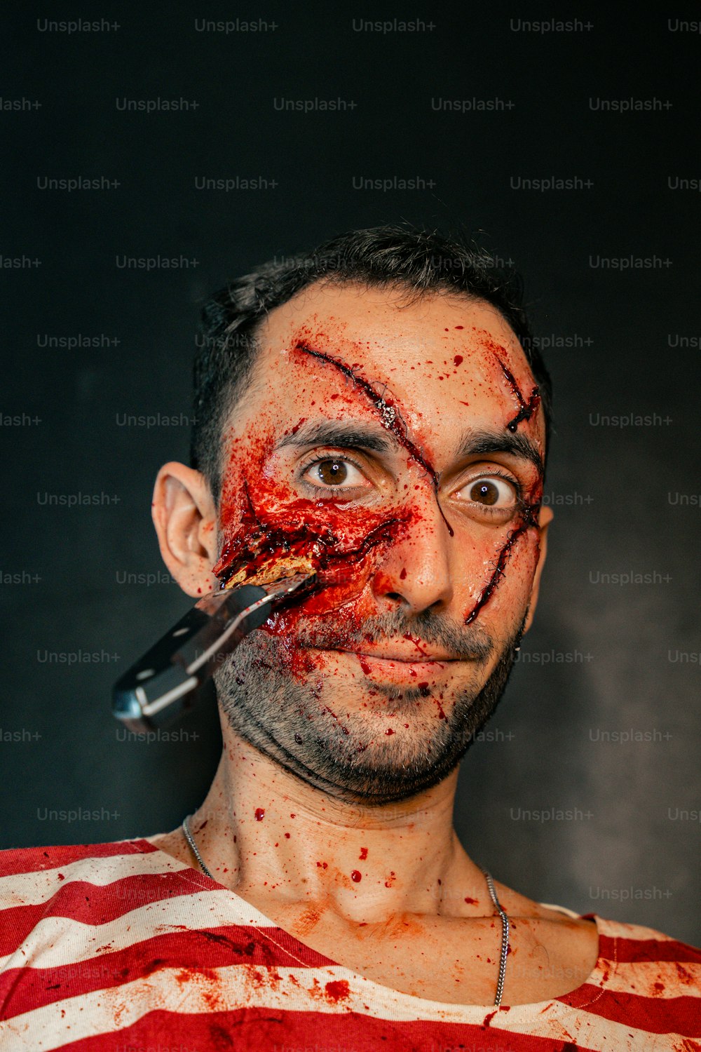um homem com uma faca na boca e sangue em todo o rosto