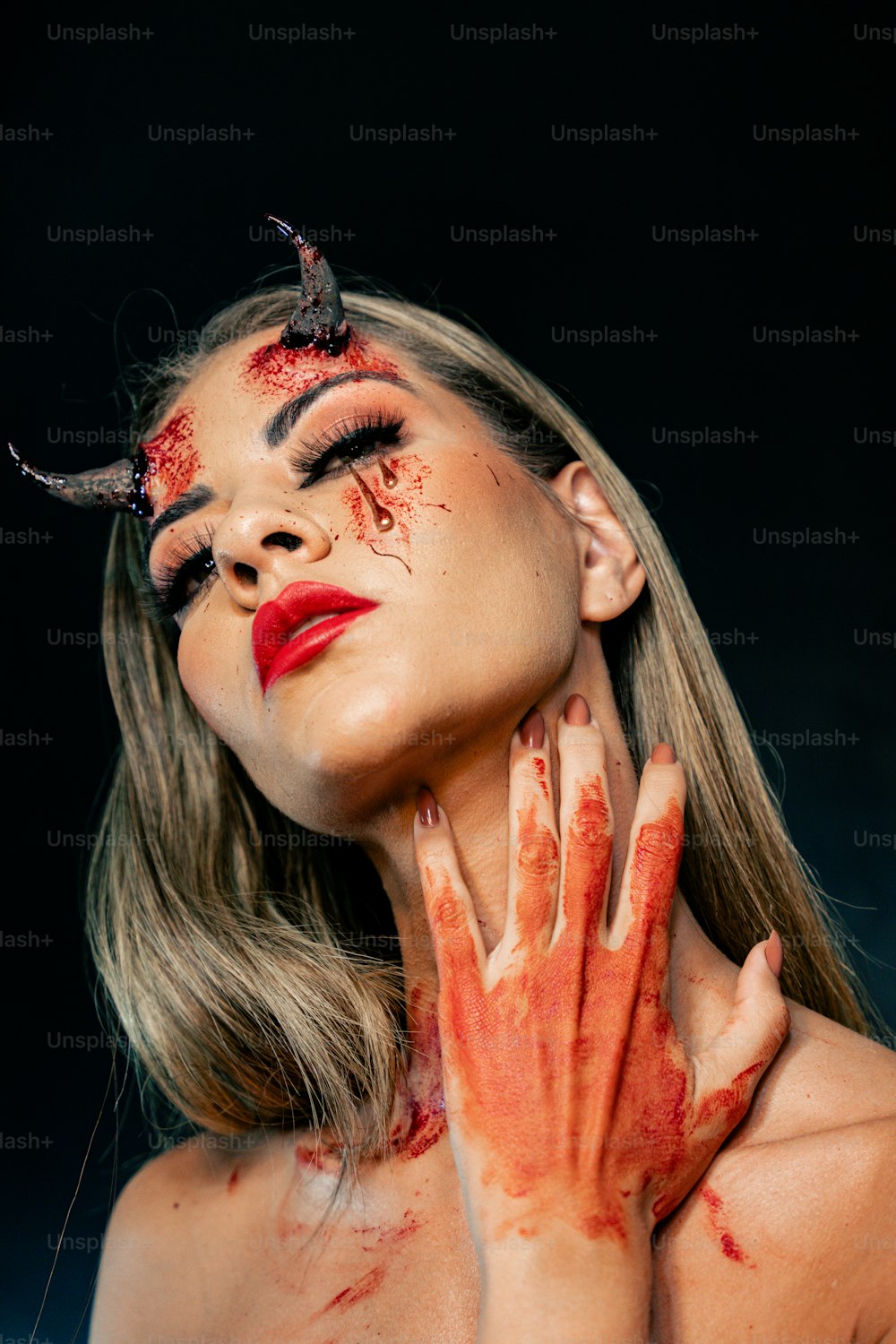 Una mujer con sangre en la cara y las manos
