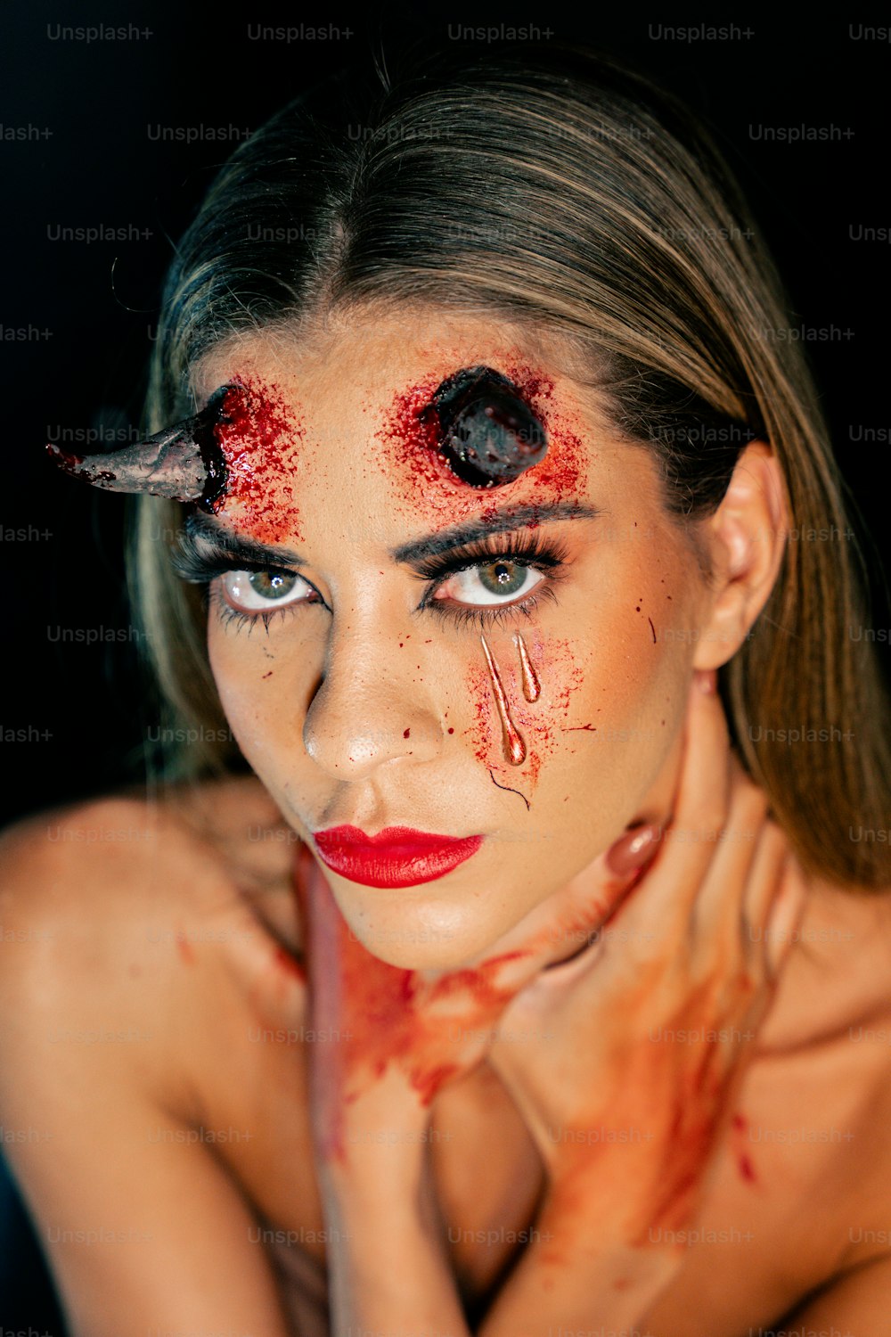 une femme maquillée et du sang sur le visage