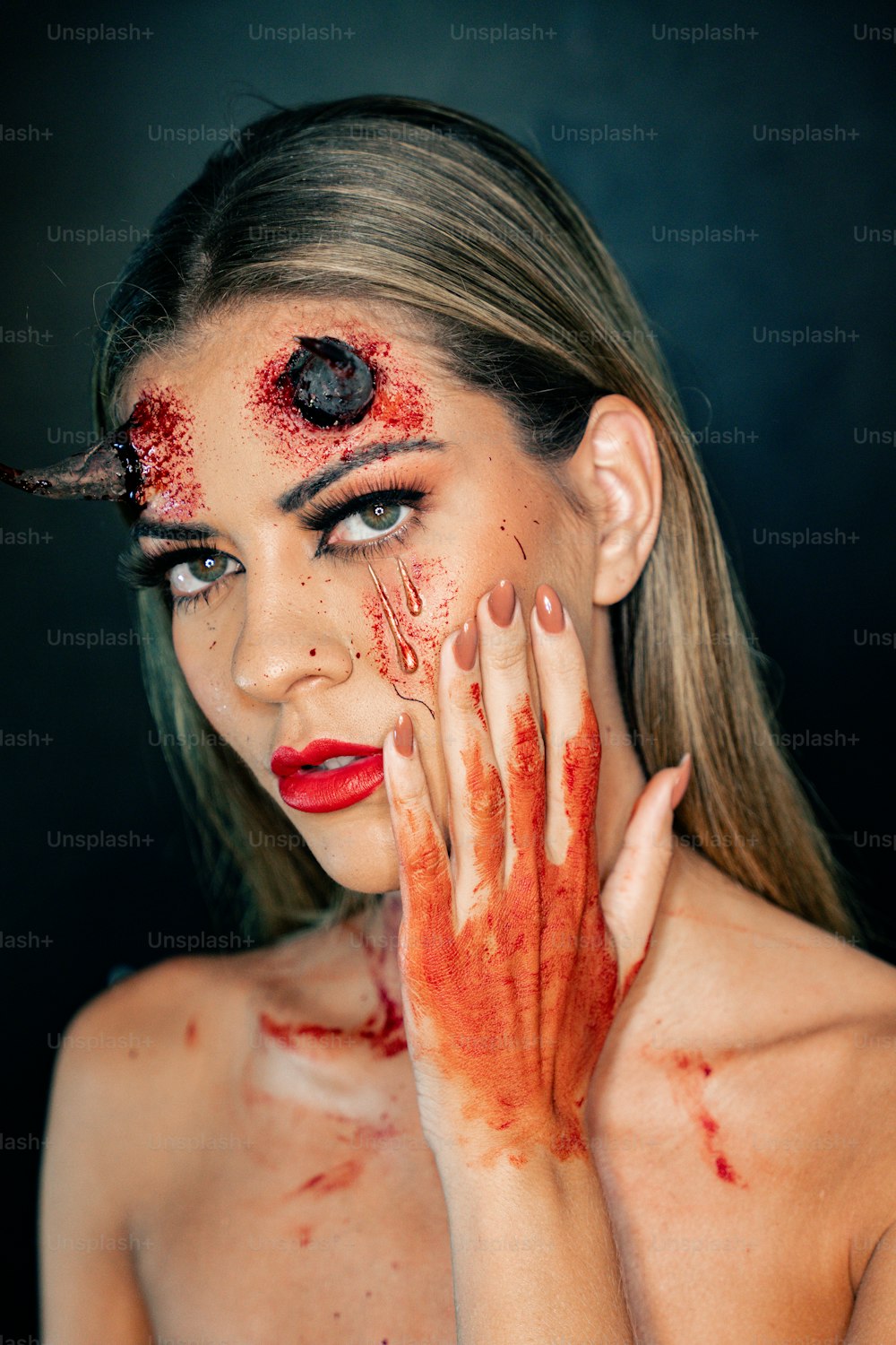 eine Frau mit Blut im Gesicht und an den Händen