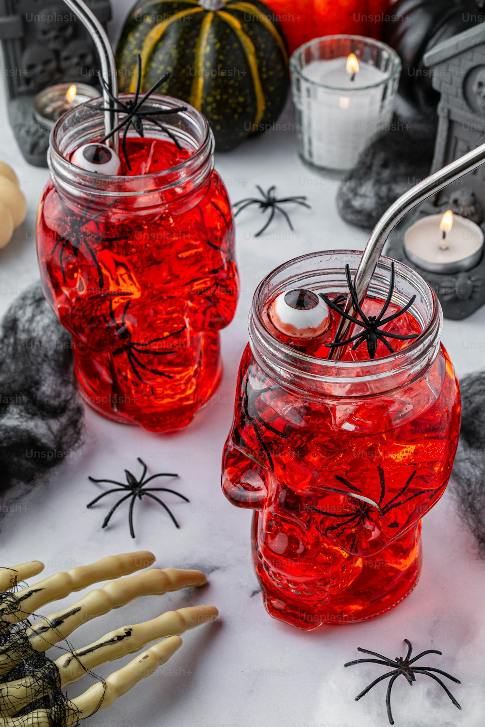 two mason jars filled with red liquid and spider webs