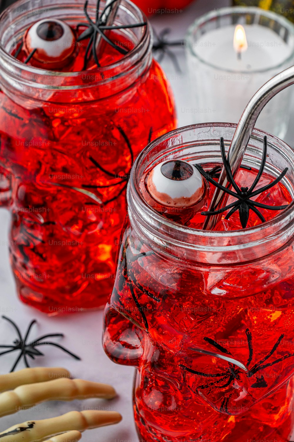 zwei Einmachgläser gefüllt mit roter Flüssigkeit mit Augen und Spinnweben