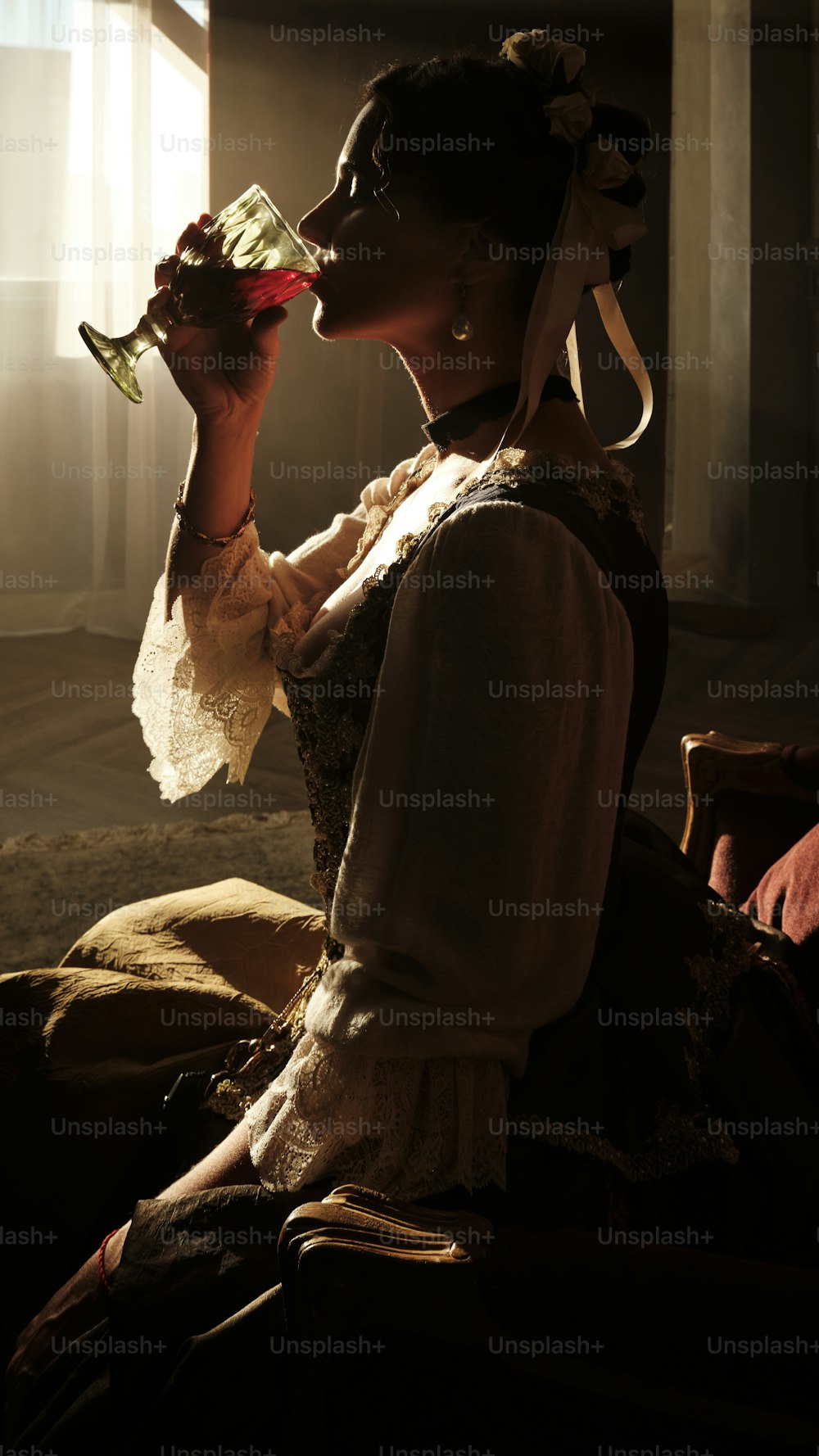 a woman sitting down drinking from a wine glass