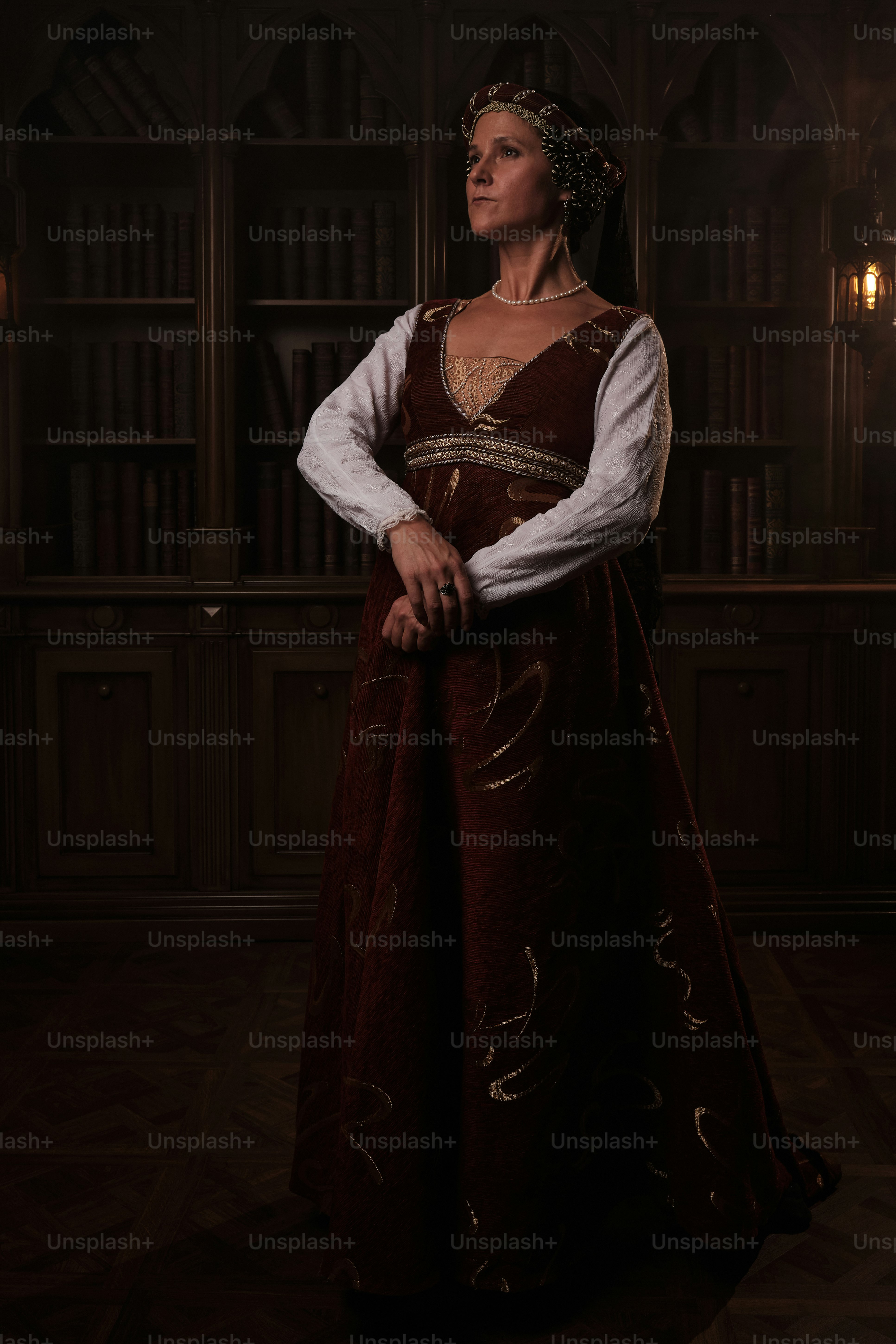 a woman in a renaissance dress standing in front of a bookshelf