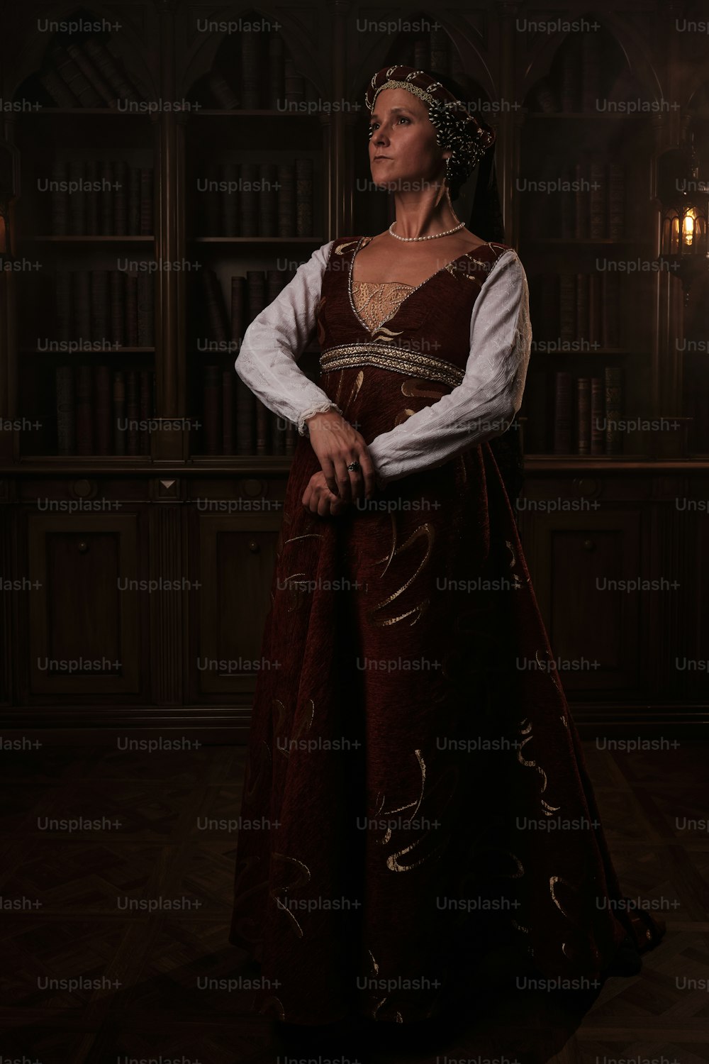a woman in a renaissance dress standing in front of a bookshelf