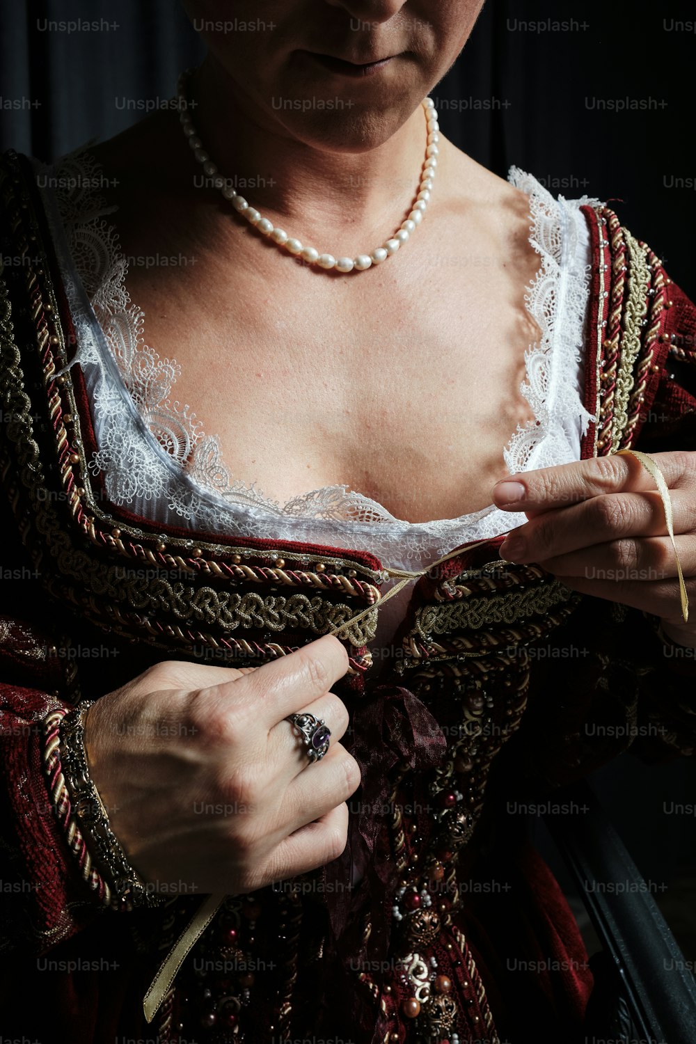 a woman in a renaissance dress is tying a necklace