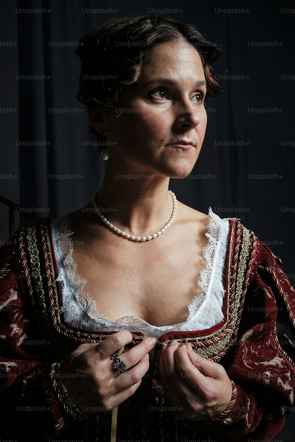 a woman in a red and white dress with a pearl necklace