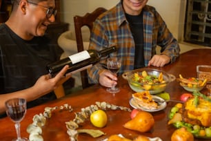 a couple of men sitting at a table with food and wine