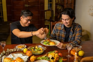 Un par de hombres sentados en una mesa con platos de comida