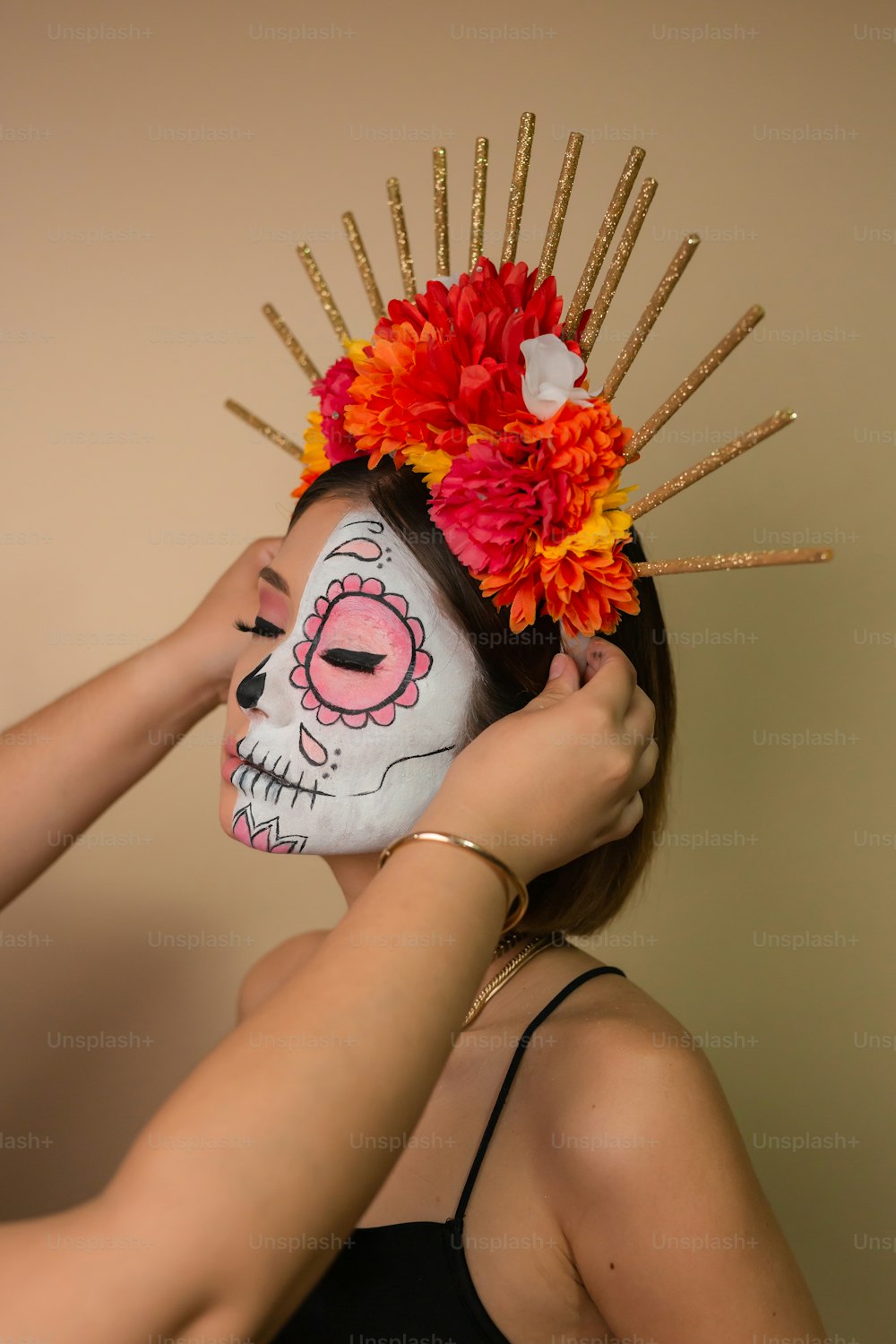 a woman is putting flowers on a skull mask