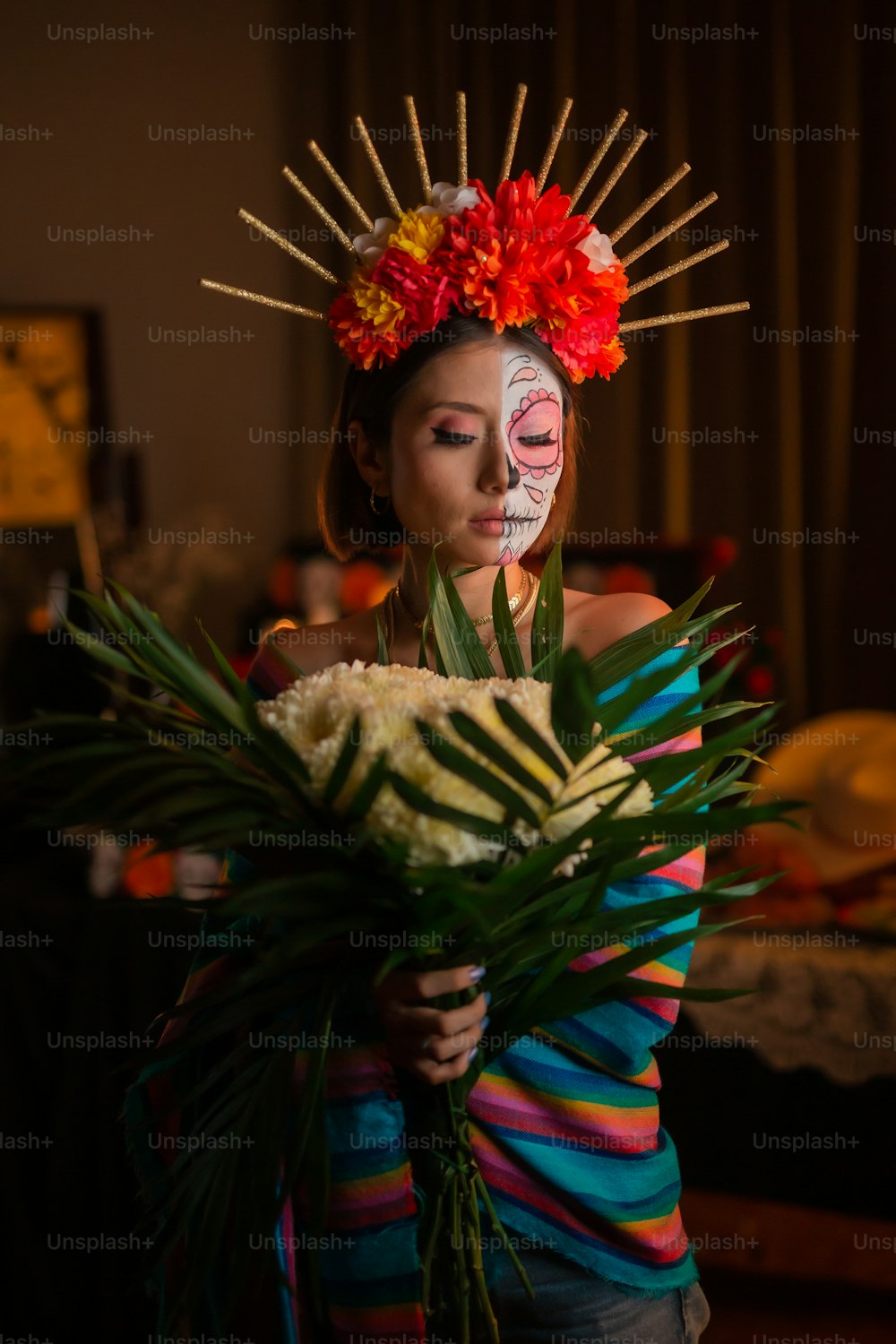 una donna con il volto dipinto che tiene un mazzo di fiori