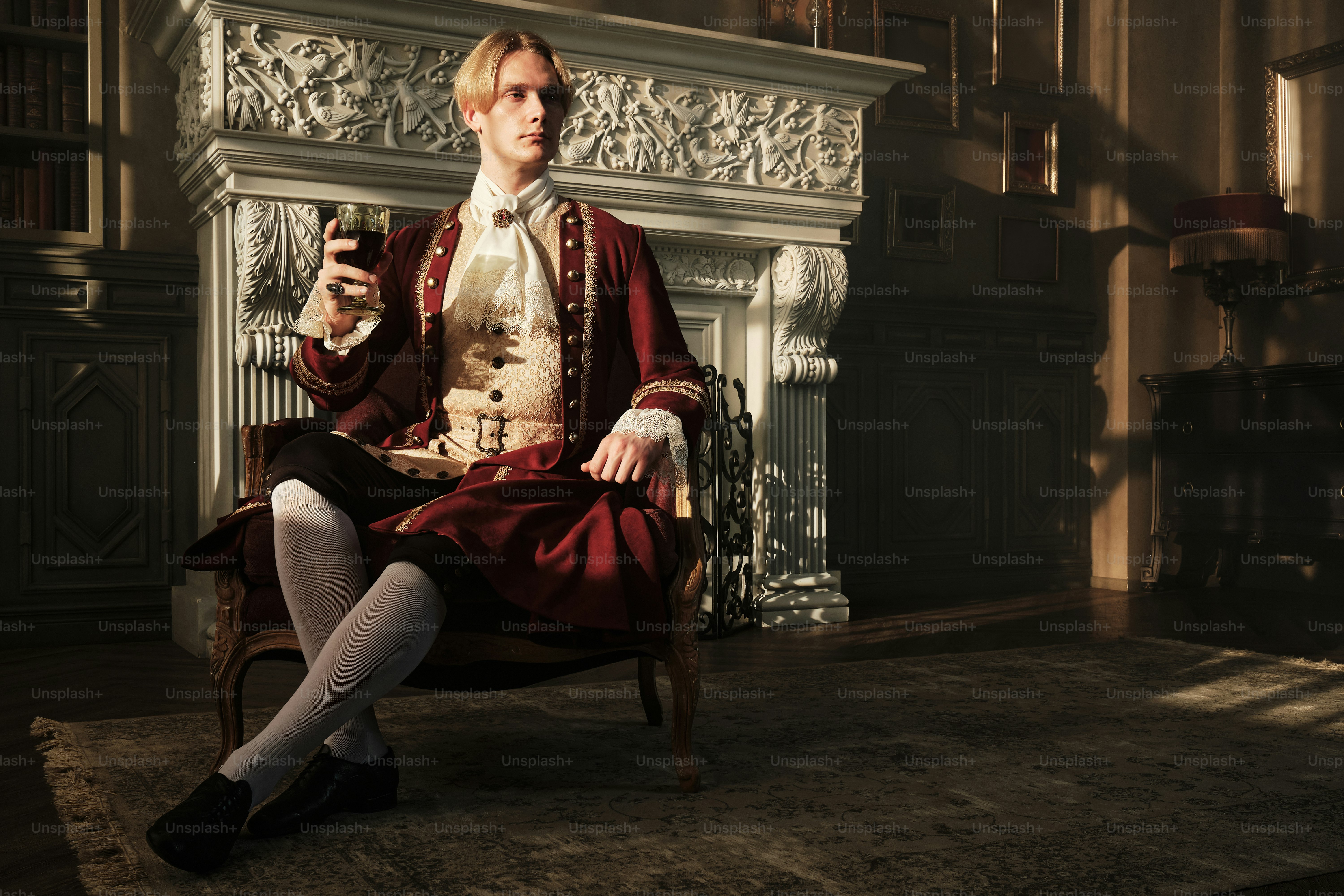 Un uomo seduto su una sedia che tiene un bicchiere di vino