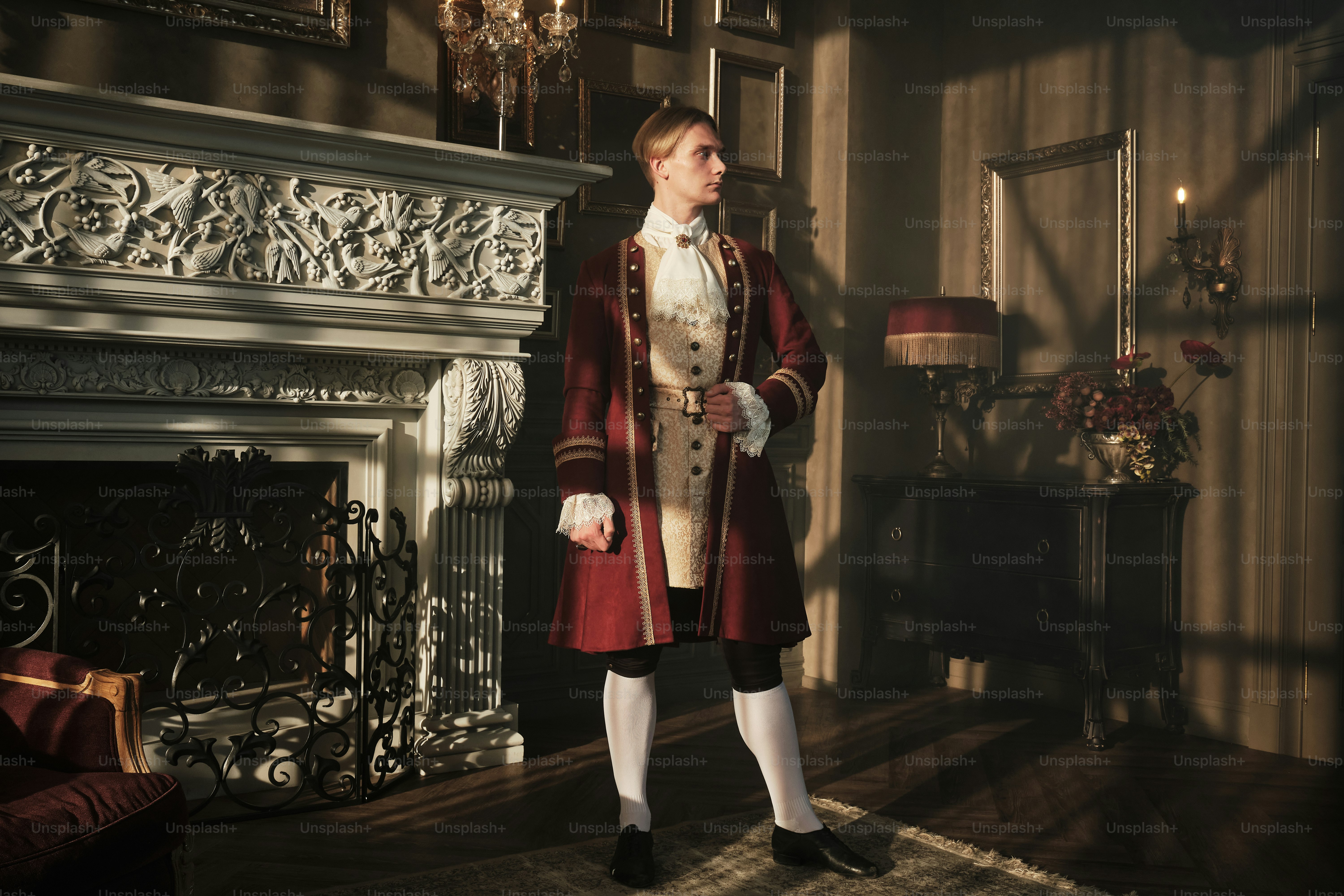 a man in a red coat standing in front of a fireplace