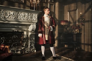 a man in a red coat standing in front of a fireplace