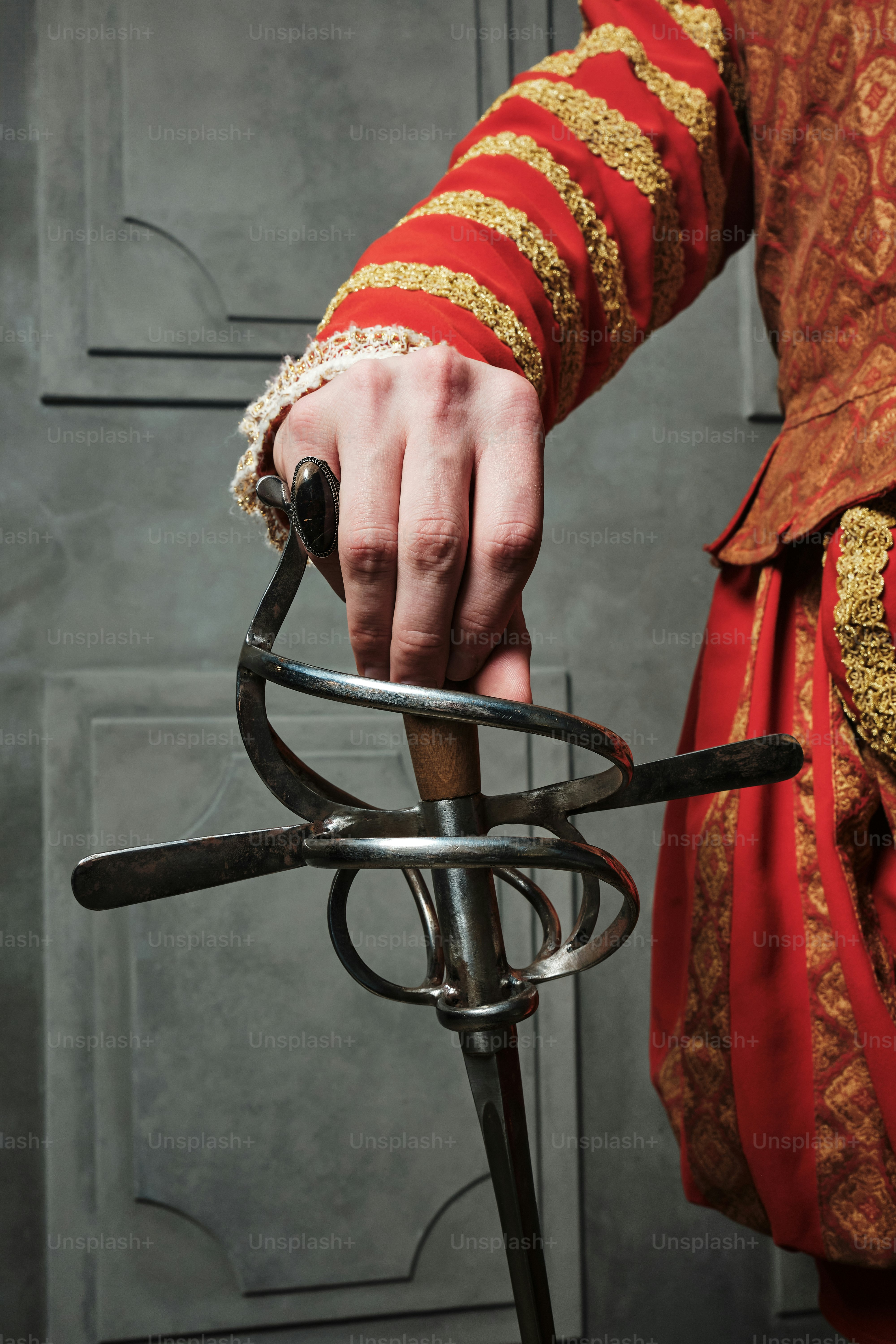 a person in a red and gold outfit holding onto a metal object