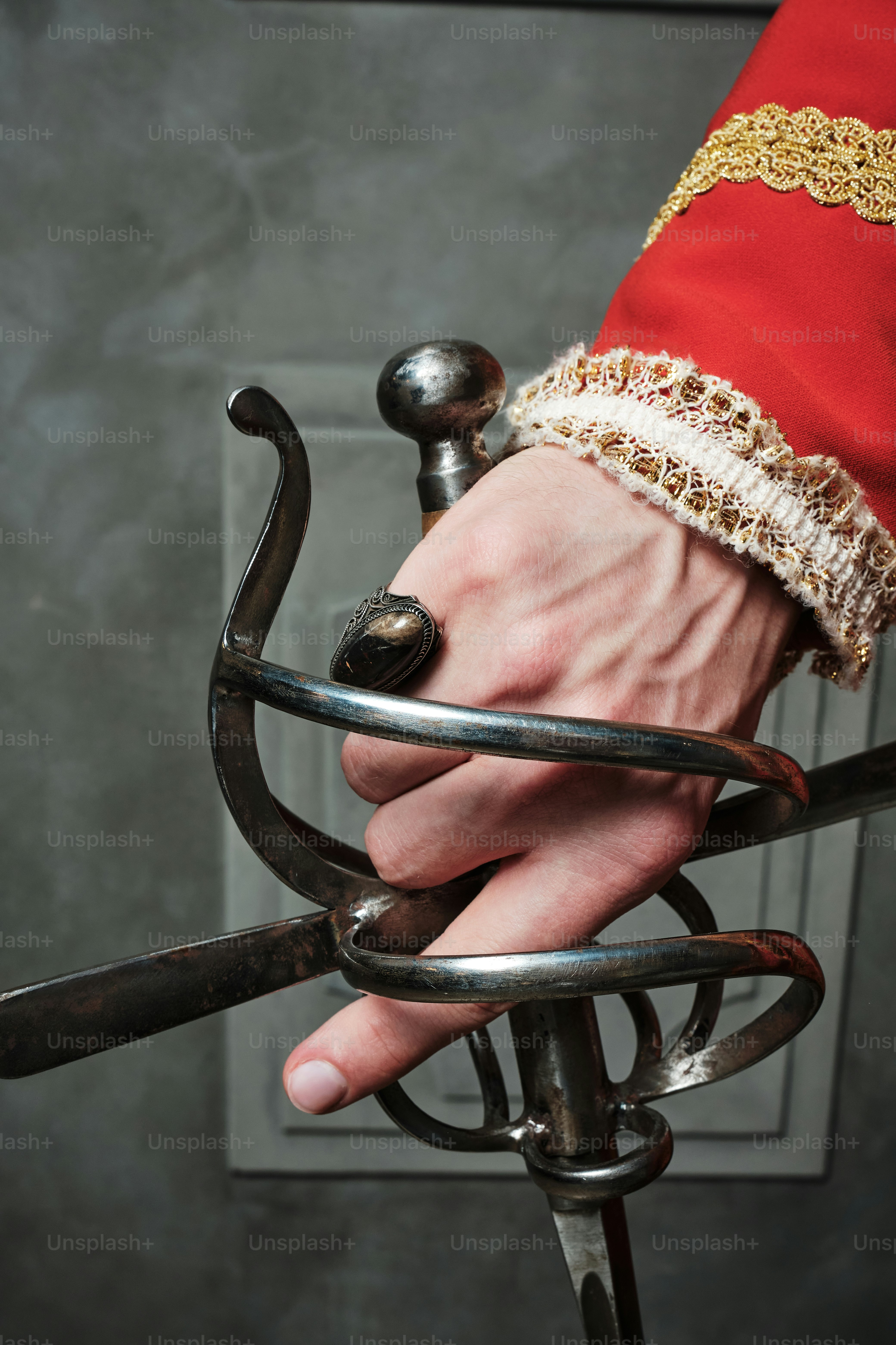 the hand of a man in medieval clothing with a sword