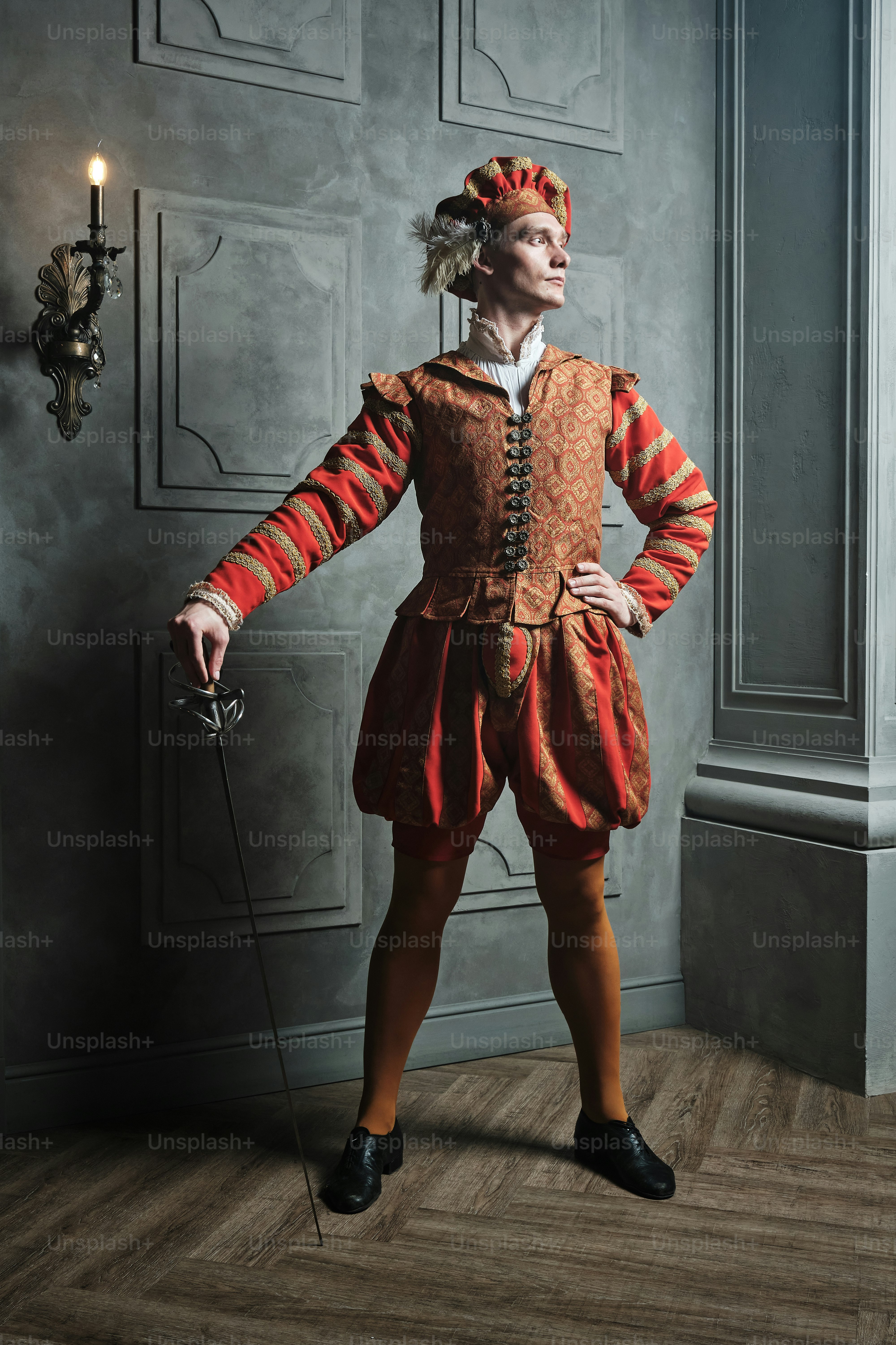 a man in a red and orange outfit standing in front of a wall