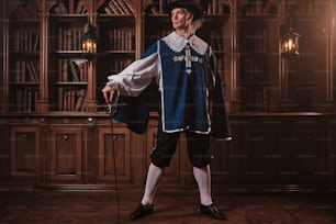 a man dressed in a renaissance costume standing in front of a bookshelf