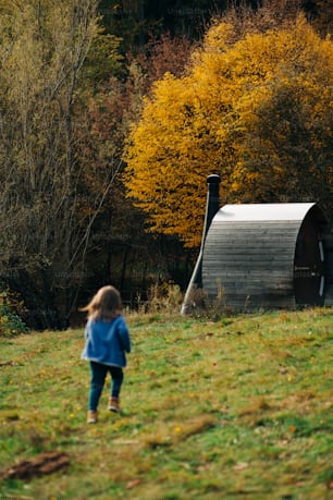 a little girl standing in a field next to a barn