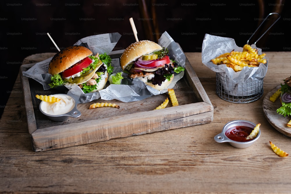 a wooden tray topped with two sandwiches and fries