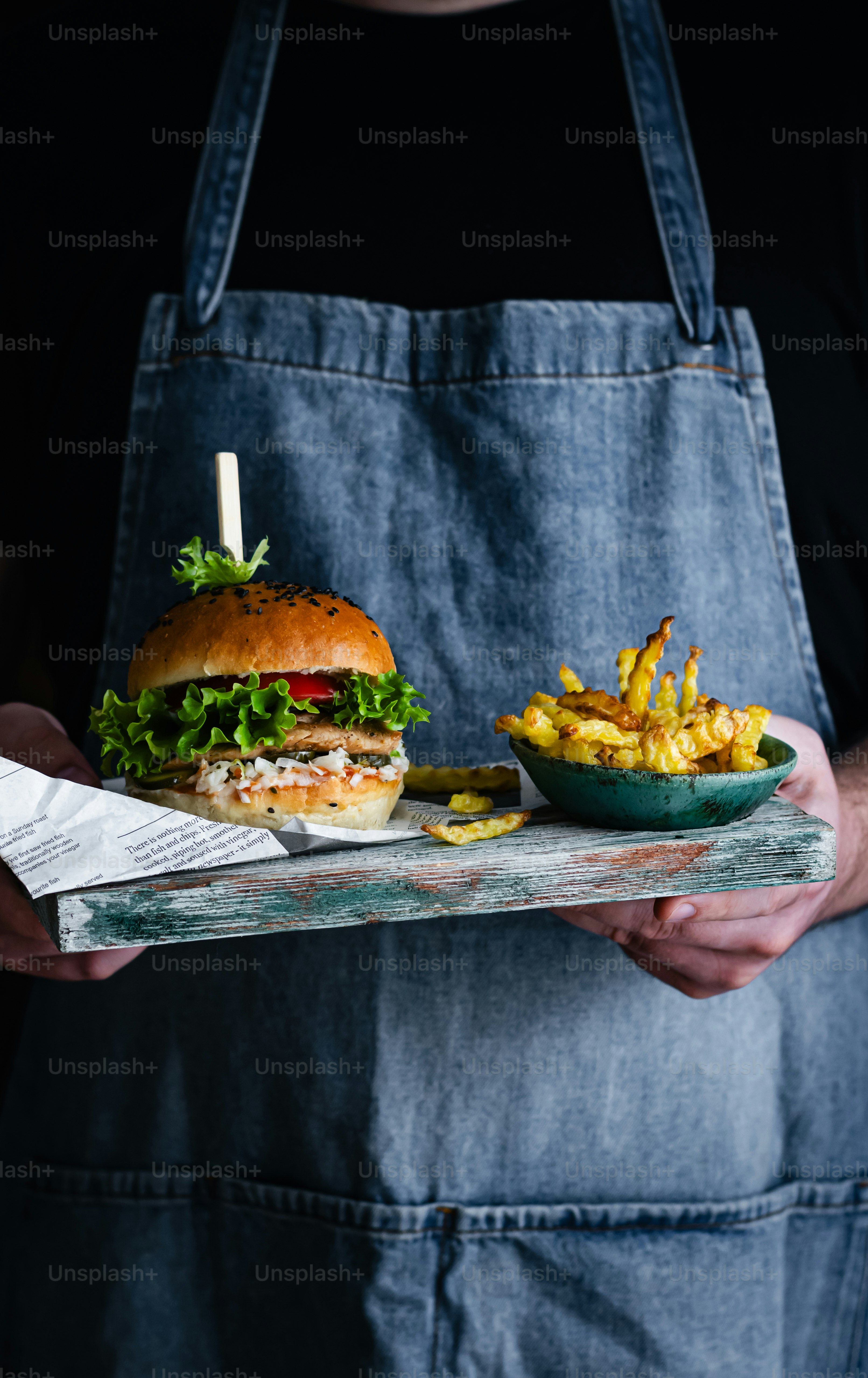 a person holding a tray with a sandwich and fries