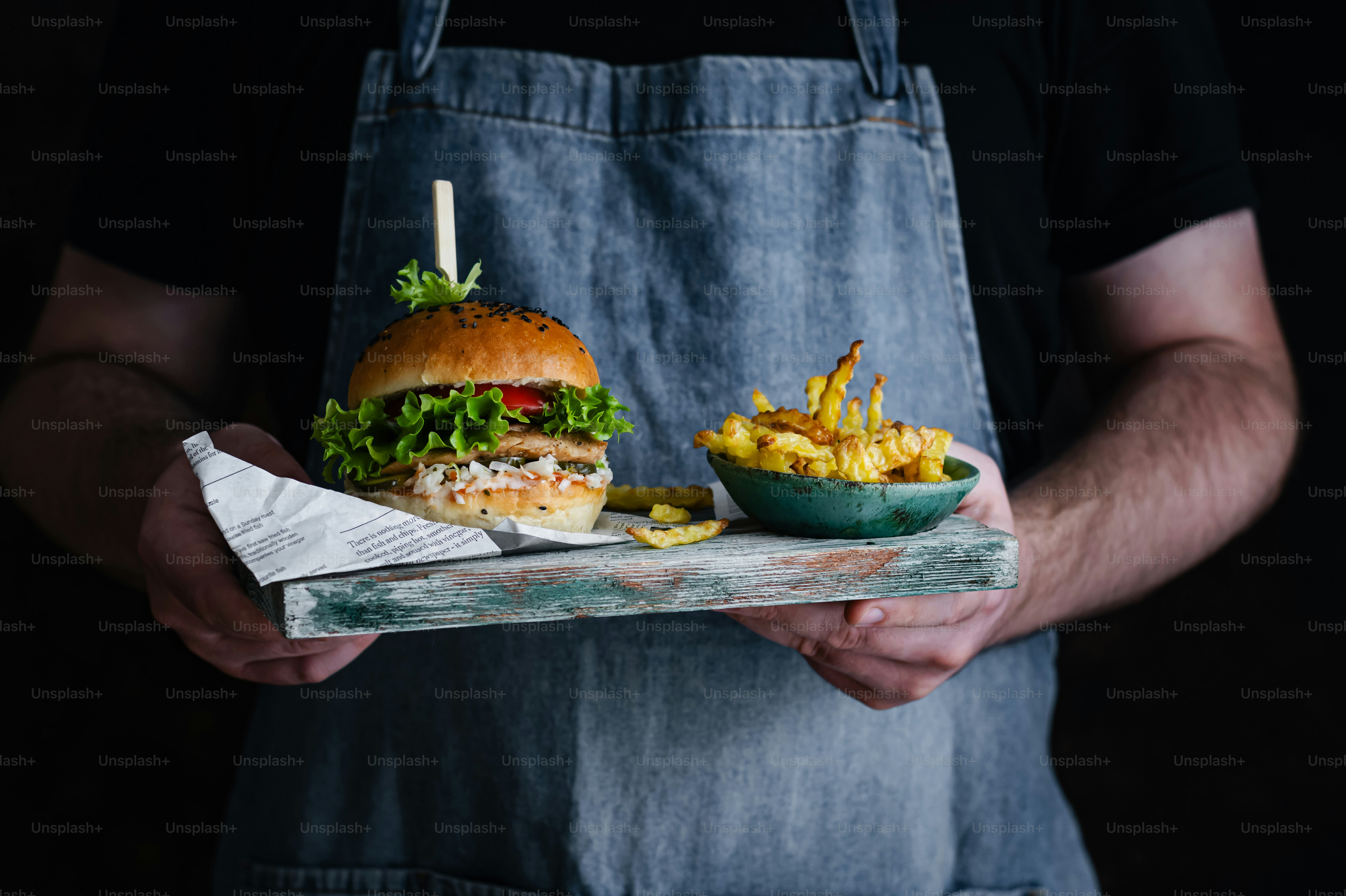 a man holding a tray with a sandwich and fries
