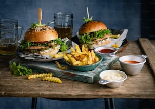 Una mesa de madera cubierta con dos hamburguesas y papas fritas