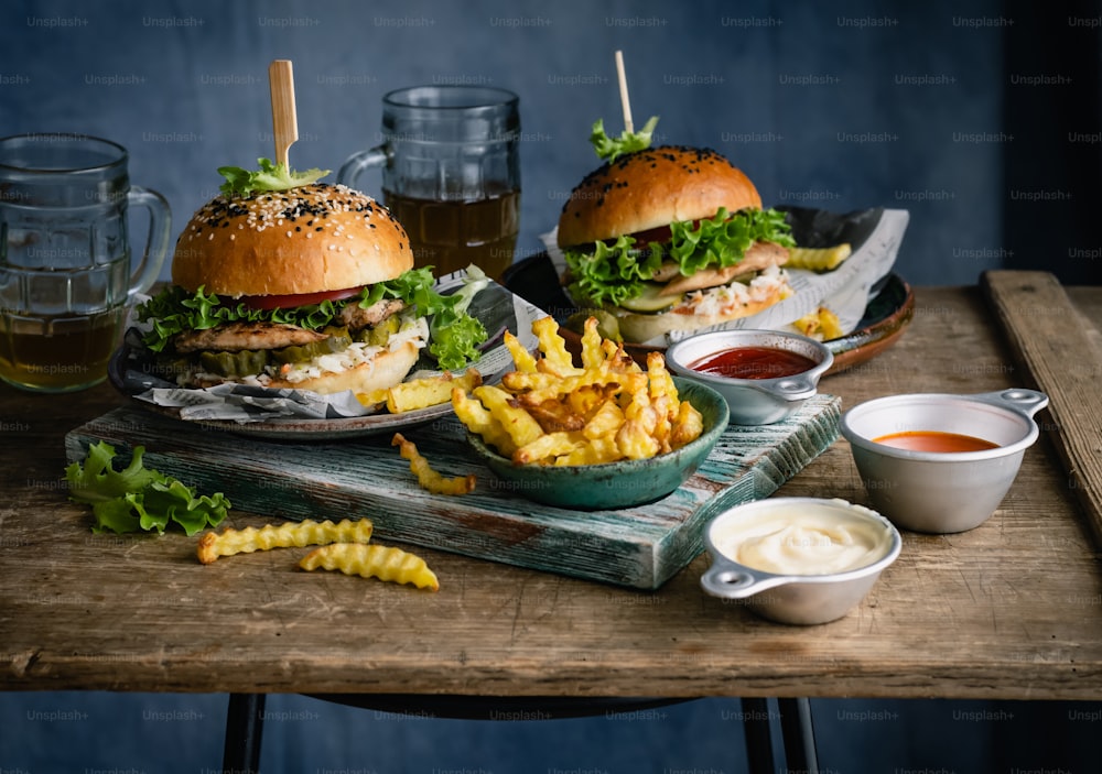 a wooden table topped with two burgers and fries