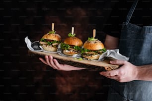 a person holding a tray with three hamburgers on it