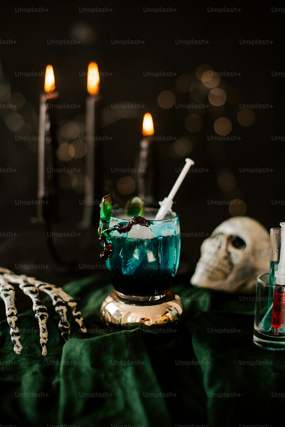 a blue liquid in a glass next to a skull