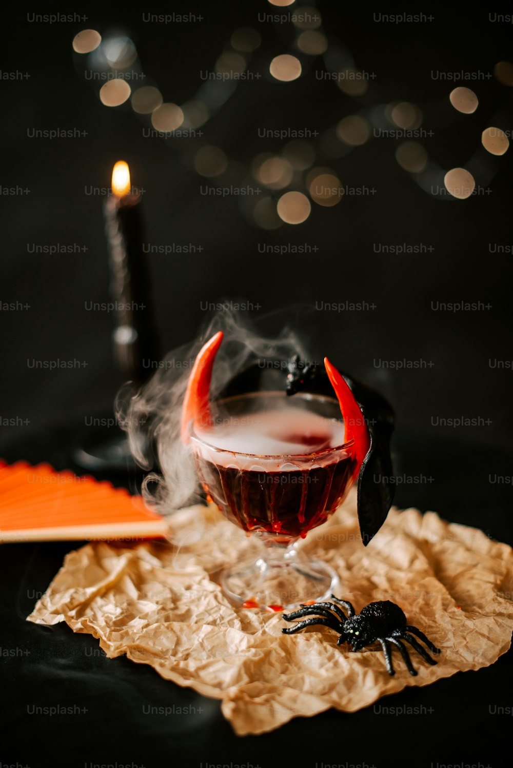 a glass of booze on a table with a candle