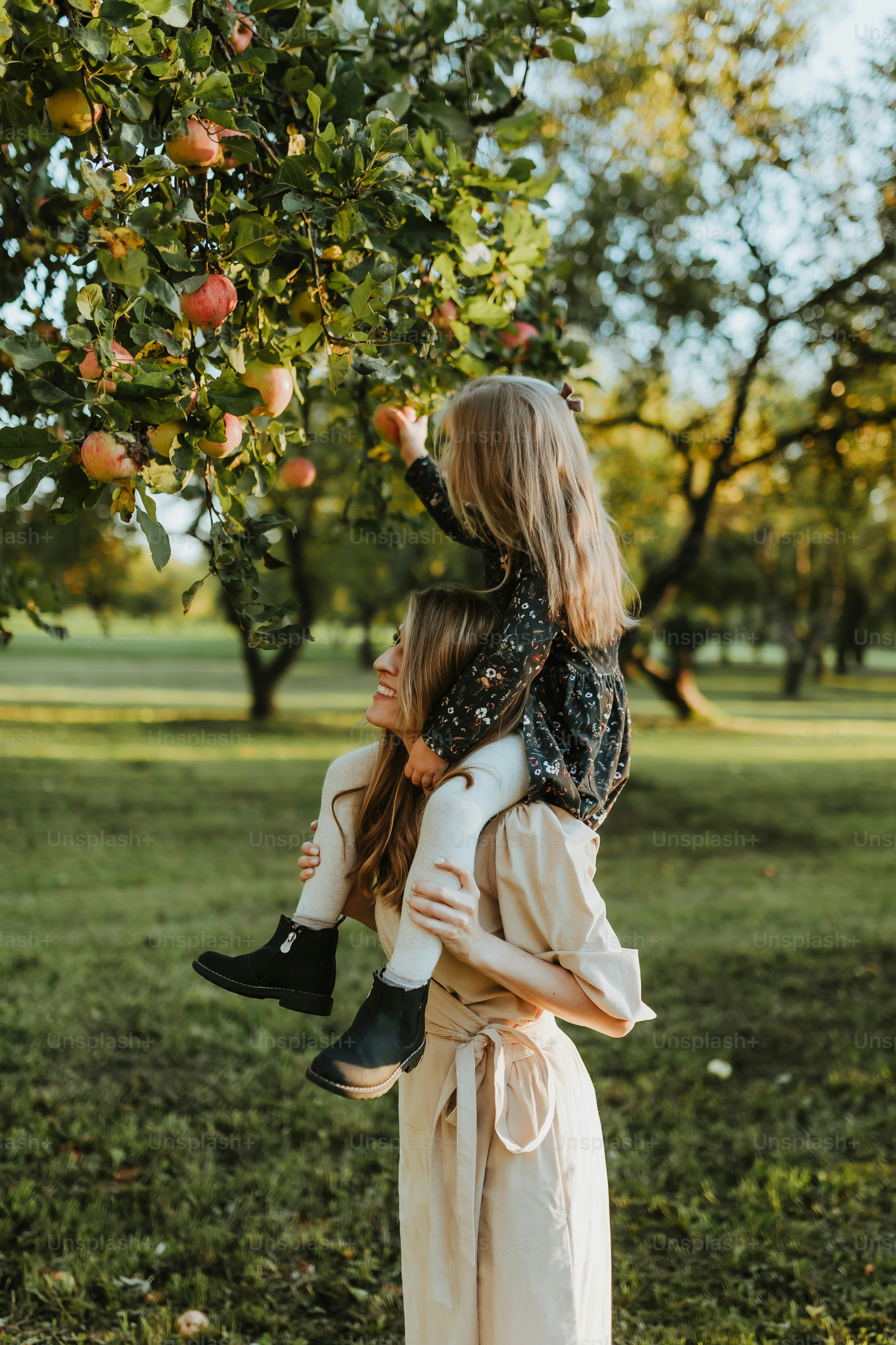 a woman holding a little girl under a tree
