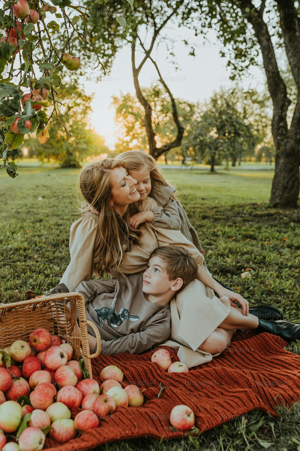 eine Frau und zwei Kinder, die auf einer Decke im Gras liegen