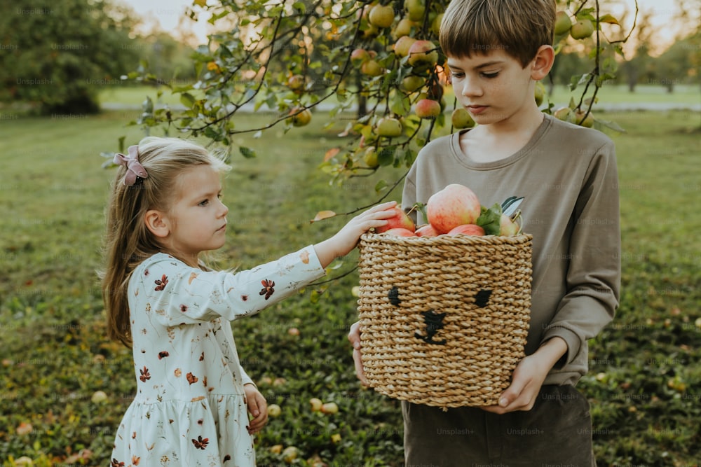 a boy and a girl holding a basket of fruit