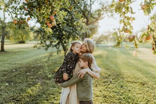a family hugging each other under an apple tree