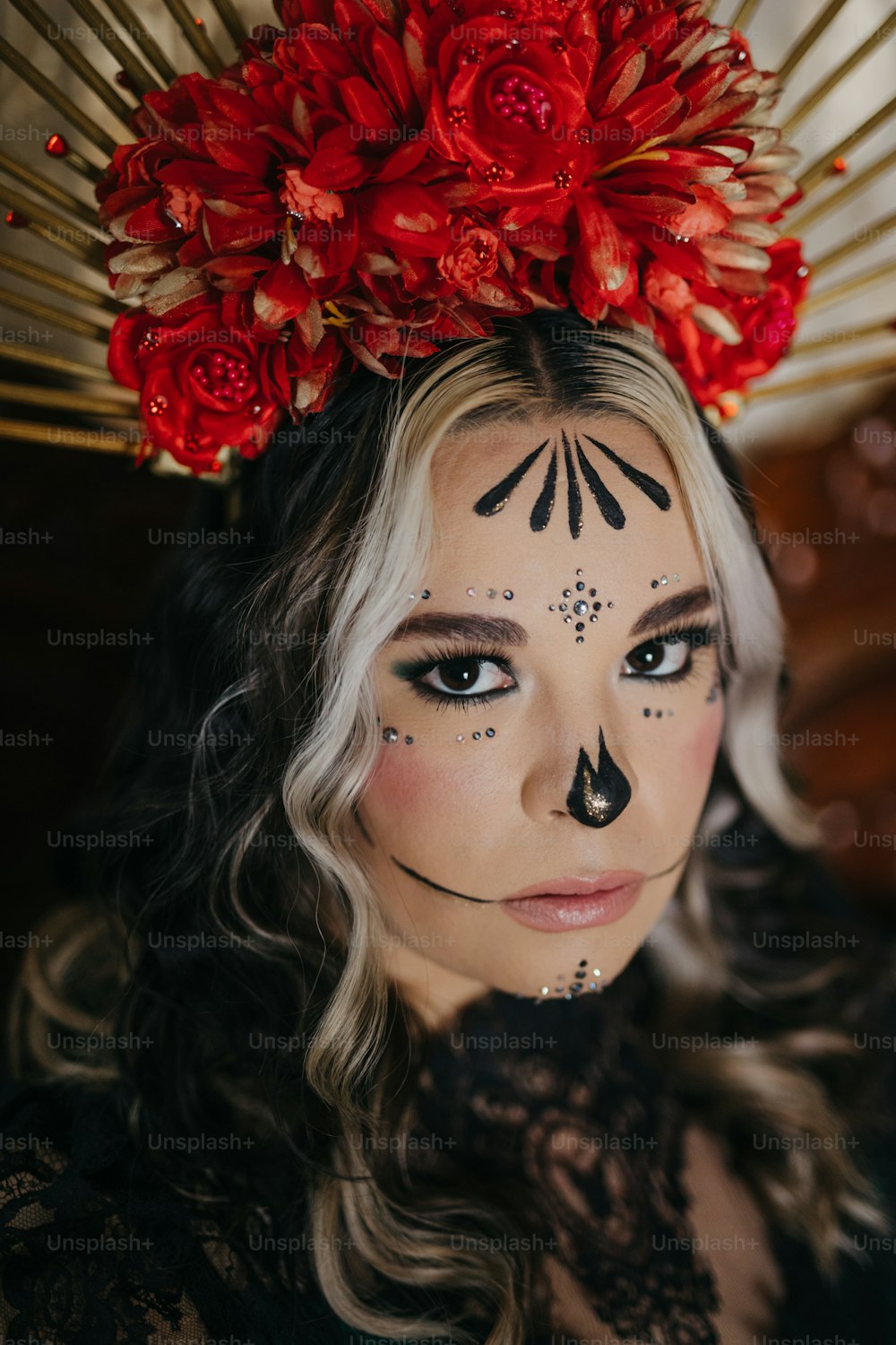 Una mujer con una pintura facial en blanco y negro y flores rojas en la cabeza