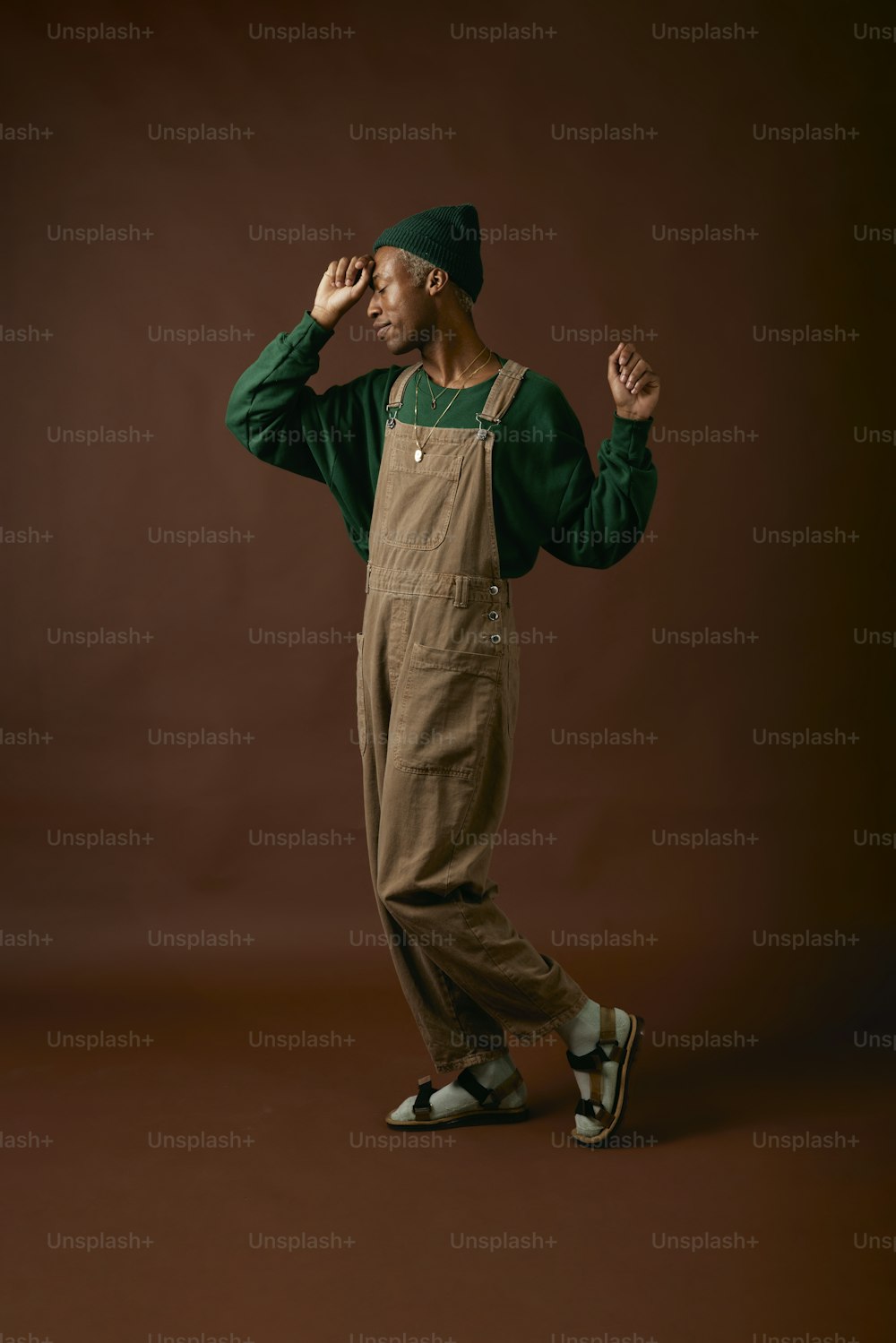 a man wearing overalls and a green hat